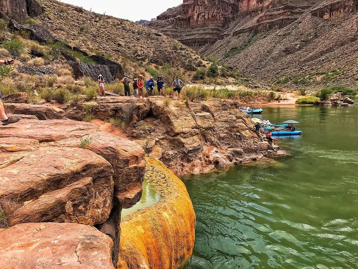 Pumpkin Spring travertine rim above the green Colorado River with rafts moored below canyon walls