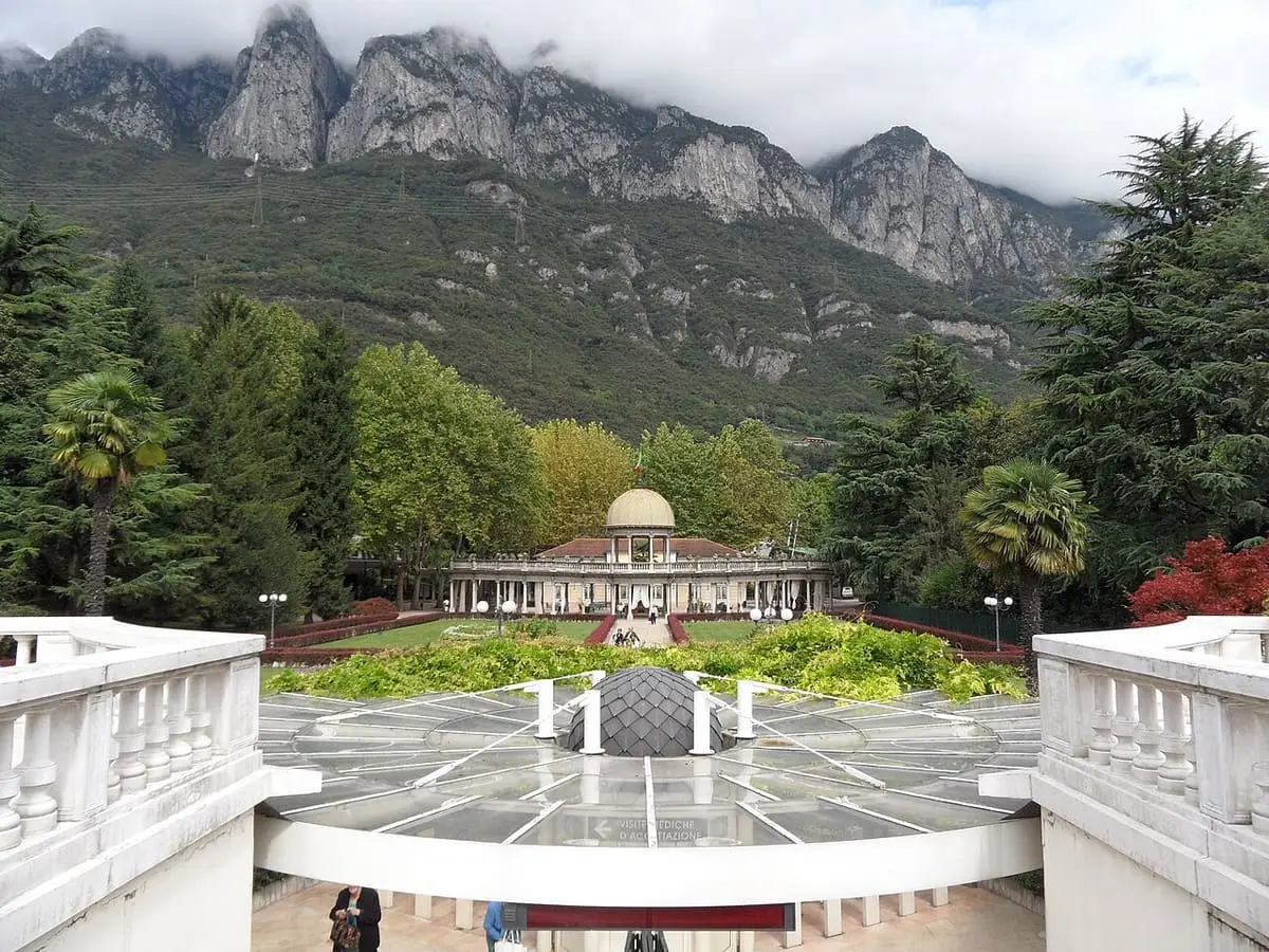 Terme di Boario gardens leading to the domed pavilion under craggy peaks