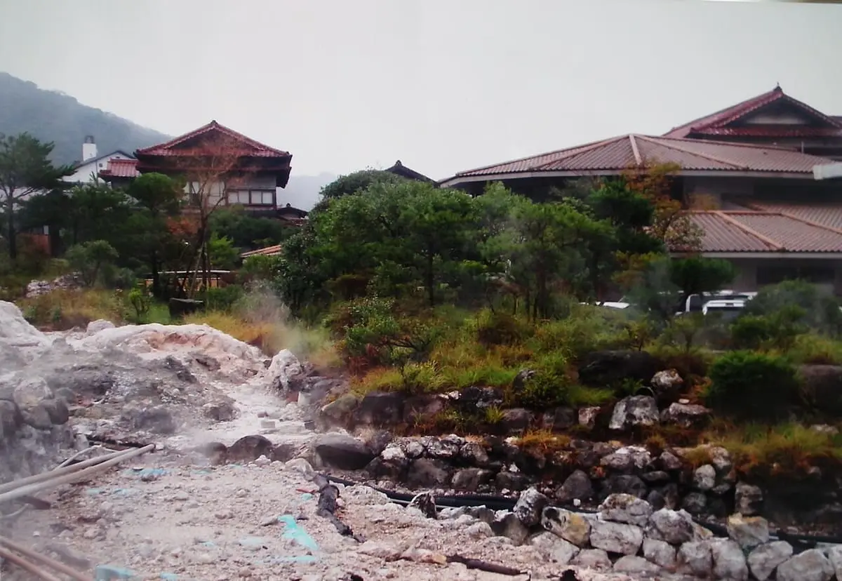 Steaming white ground of the Unzen hells with hotel roofs of Unzen Onsen beyond