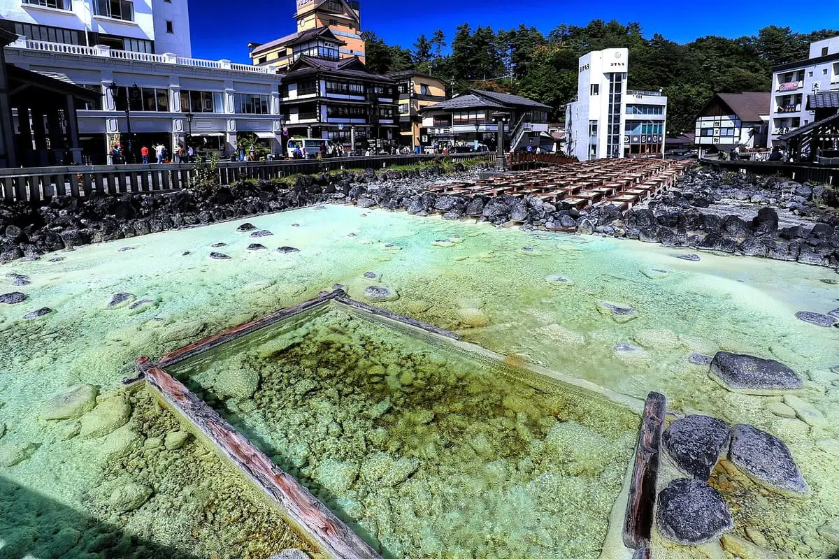 Pale green hot spring water flowing through wooden channels at the Yubatake in Kusatsu Onsen