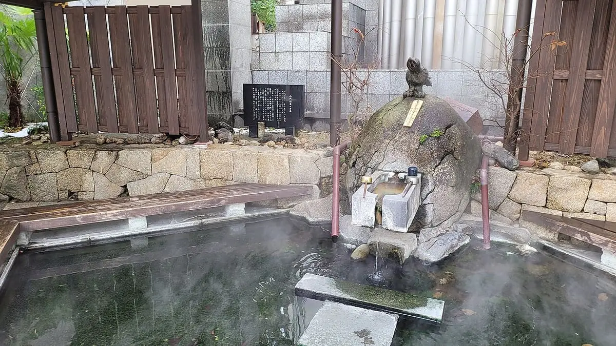Steaming hot spring basin with a stone fountain in Yamashiro Onsen