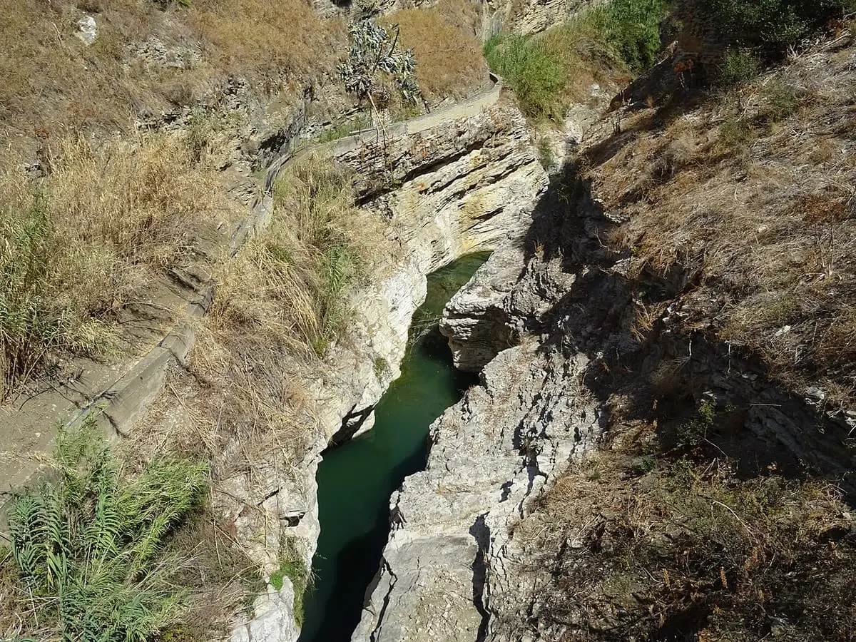 Narrow green channel of the Fiume Caldo cutting through layered rock near the Segestan baths
