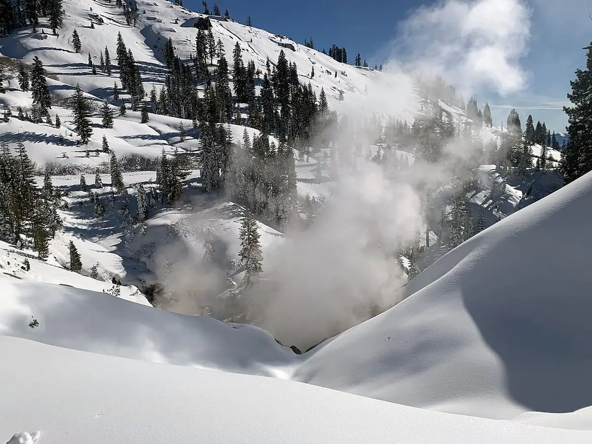 Steam rising from Sulphur Works in a snowy ravine among conifers in Lassen Volcanic National Park