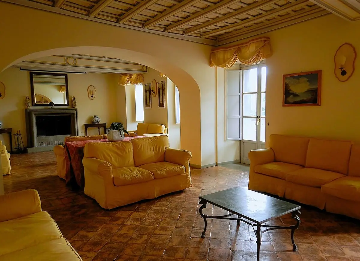 Sitting room with yellow sofas and a fireplace inside the historic Albergo Terme di Stigliano