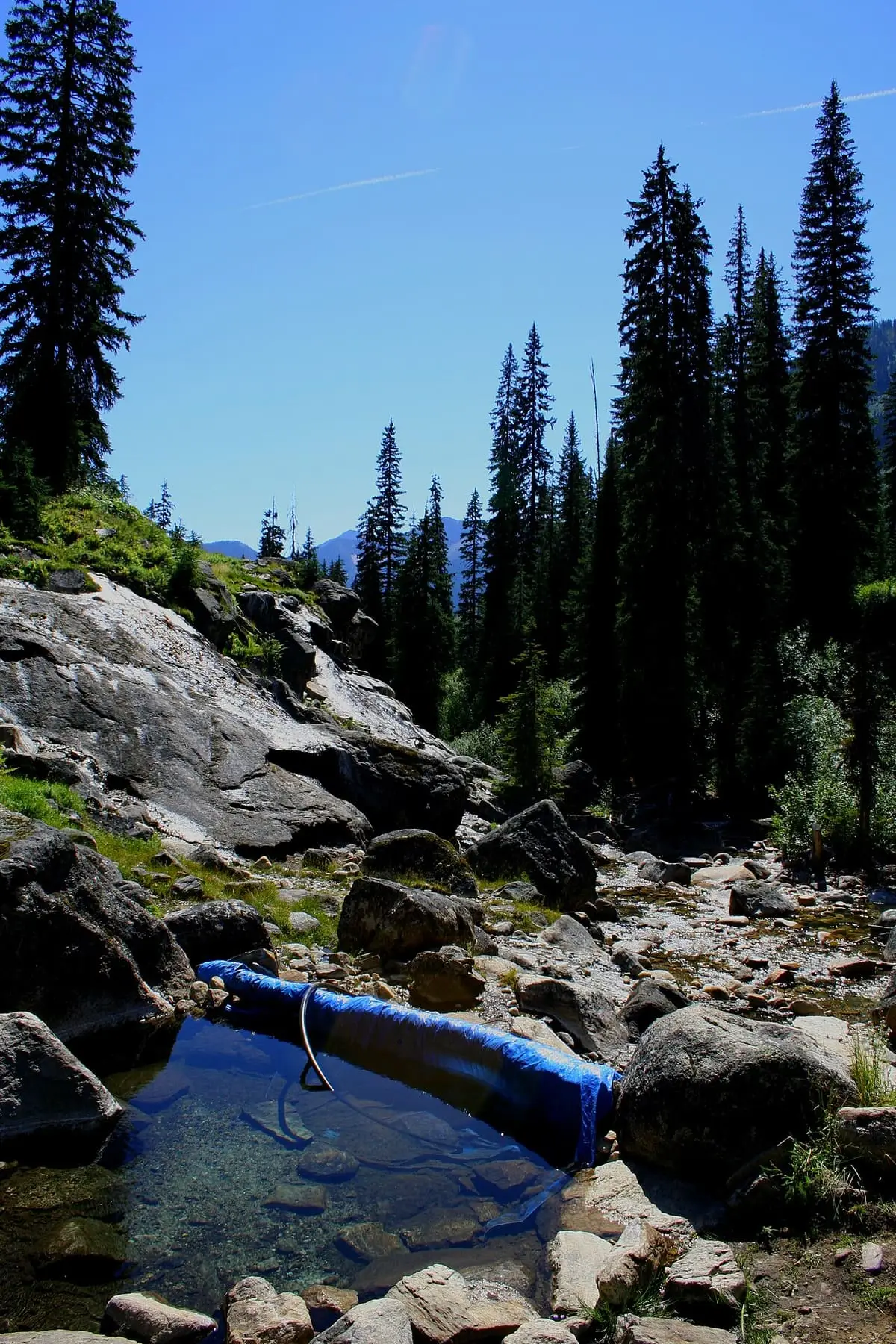 Small rock pool lined with blue tarp among boulders at Dewar Creek Hot Springs