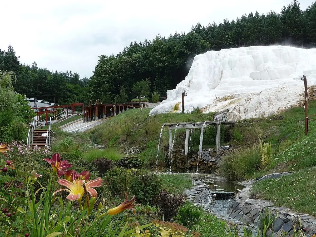 White travertine mound formed by the thermal spring at Egerszalók beside a garden stream