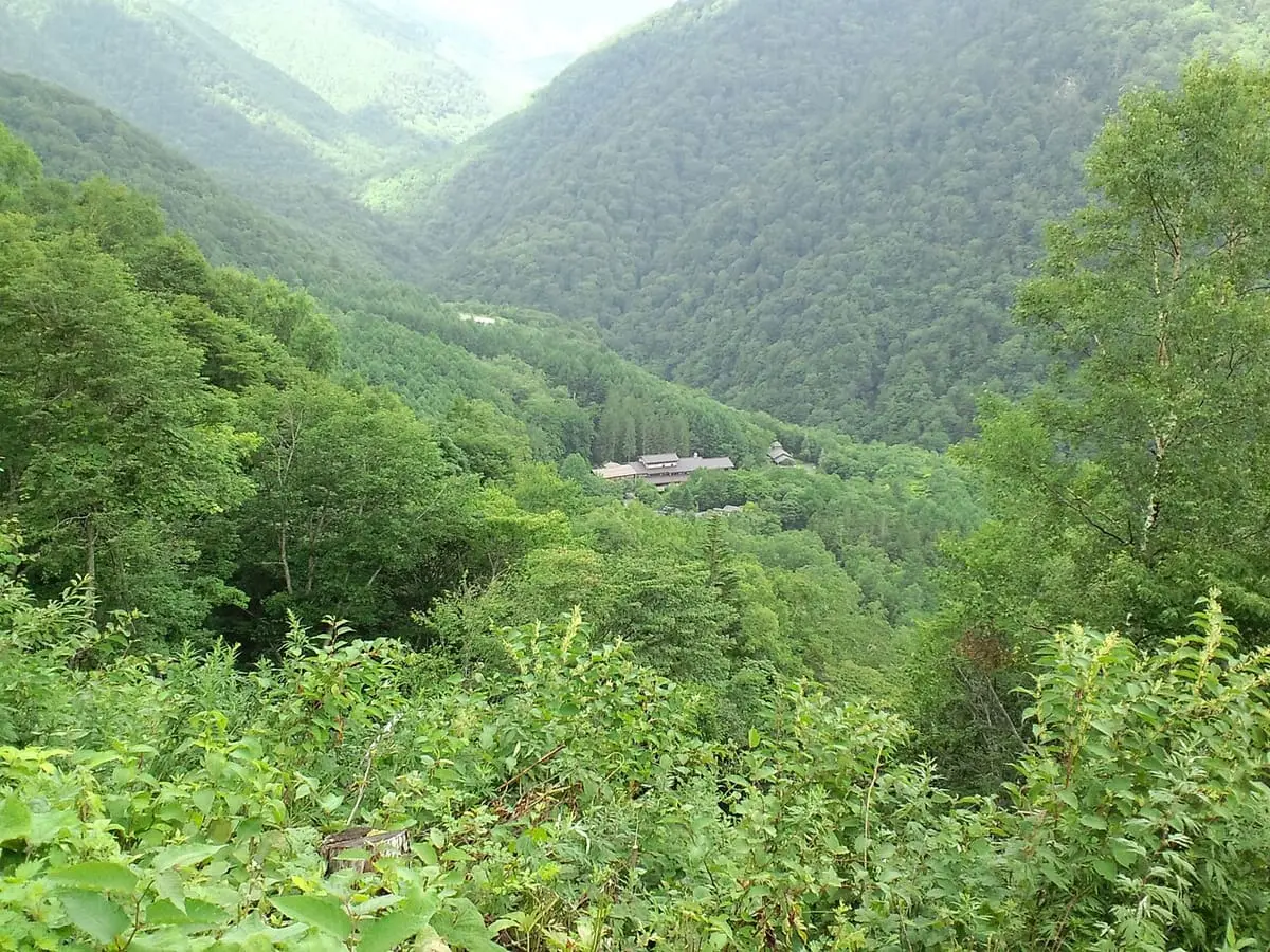 Awanoyu inn seen far below in a deep forested mountain valley at Shirahone Onsen