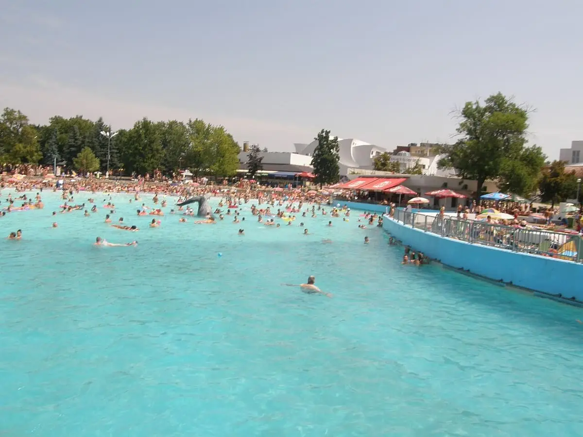 Wide turquoise outdoor pool stretching across the Hungarospa lido on a summer day