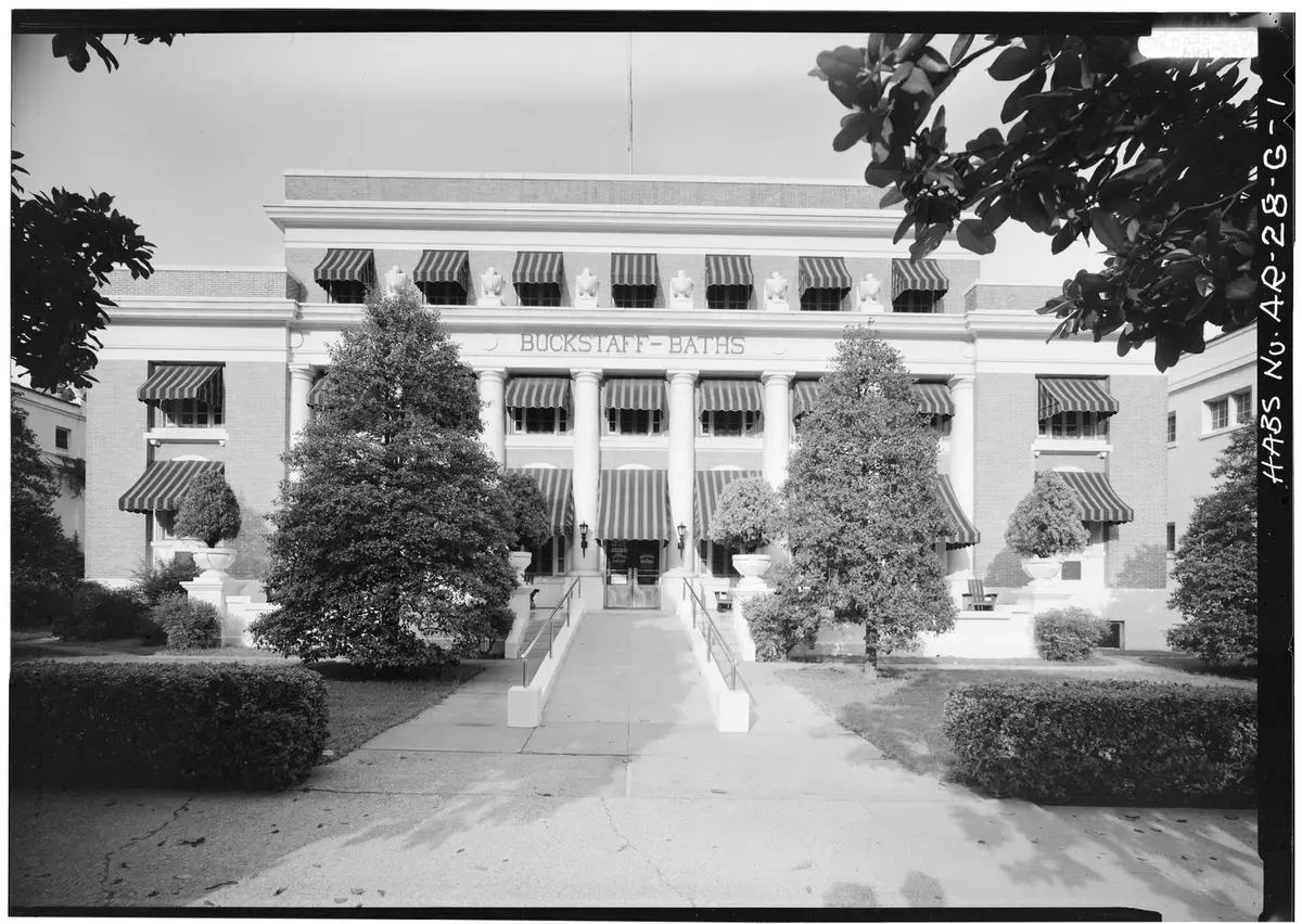 Historic black and white view of the Buckstaff Bathhouse west front behind trees and a walkway