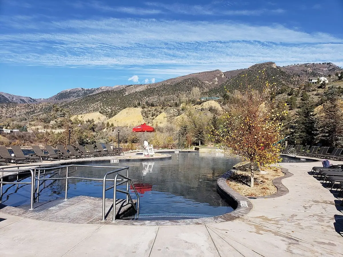 Large mineral pool under blue sky with hills behind at Iron Mountain Hot Springs