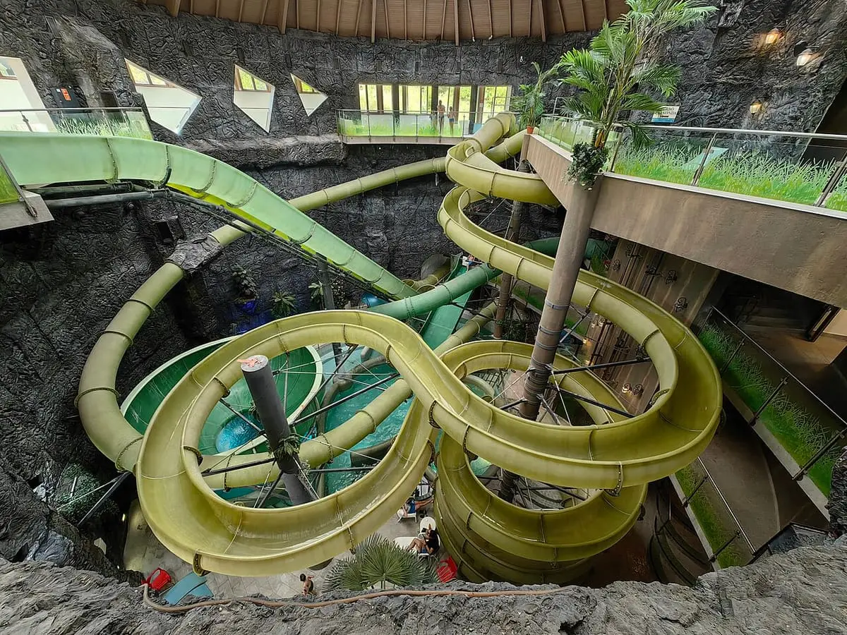Green spiral water slides winding through the open rock courtyard of the Cascade bath at Demjén