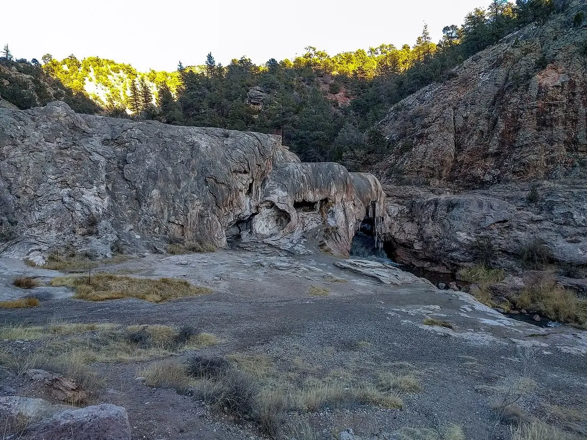 Broad travertine mound of Soda Dam beneath forested canyon walls in the Jemez Mountains