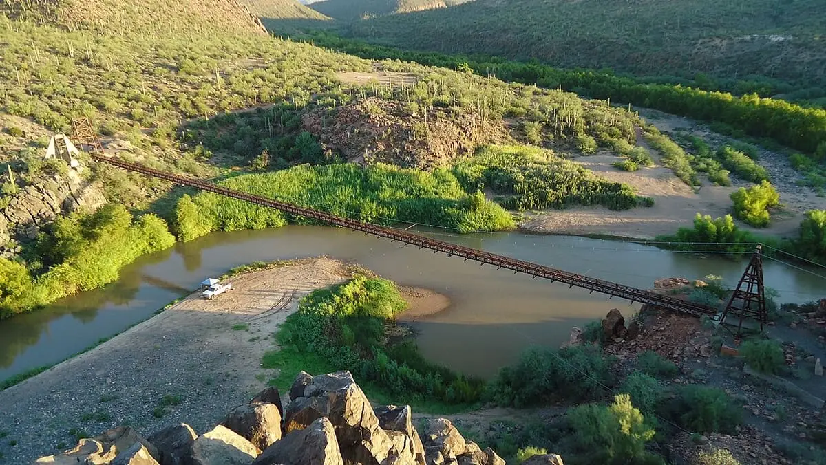 Hilltop view of the Sheep Bridge suspension footbridge spanning the green Verde River valley