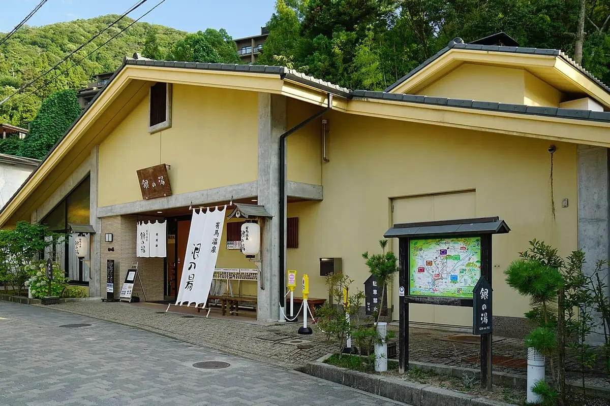 Cream colored Gin no Yu bathhouse building and signboard on a quiet lane in Arima Onsen