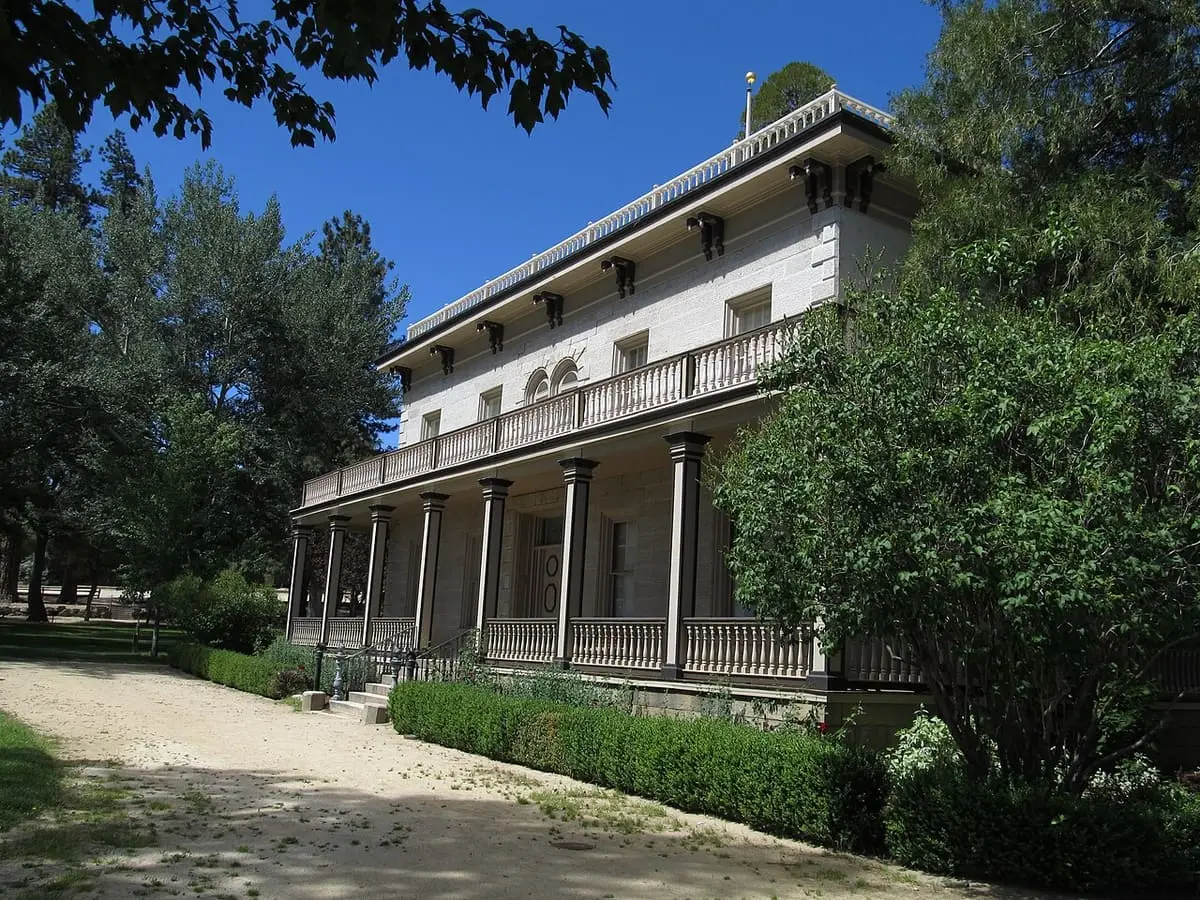Bowers Mansion stone facade and columned porch framed by trees under deep blue sky