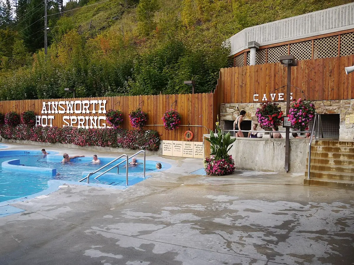 Outdoor hot pool beside the Ainsworth Hot Springs sign and the stone entrance to the caves