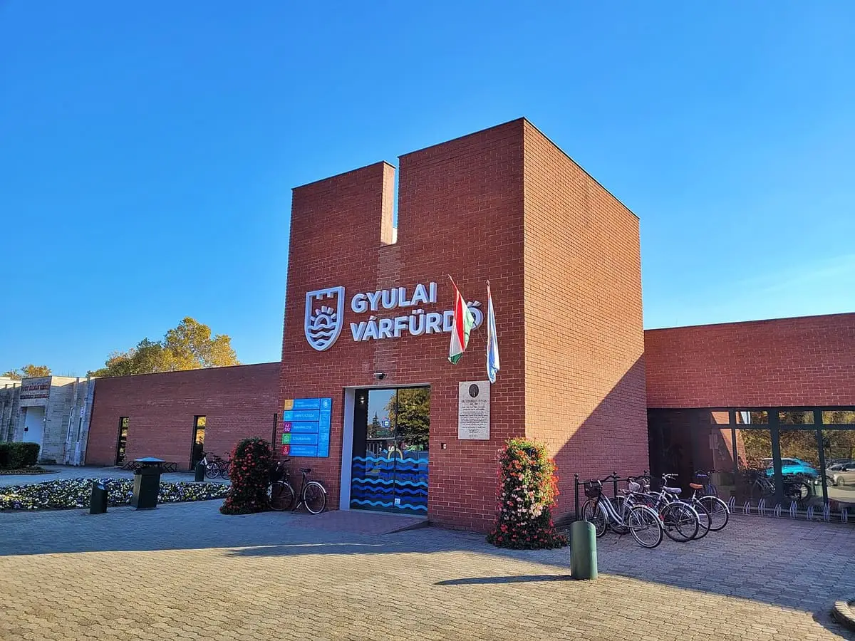 Red brick main entrance of the Gyulai Várfürdő under a clear blue sky