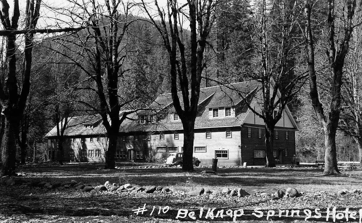 Historic black and white view of the Belknap Springs Hotel among bare trees in 1949