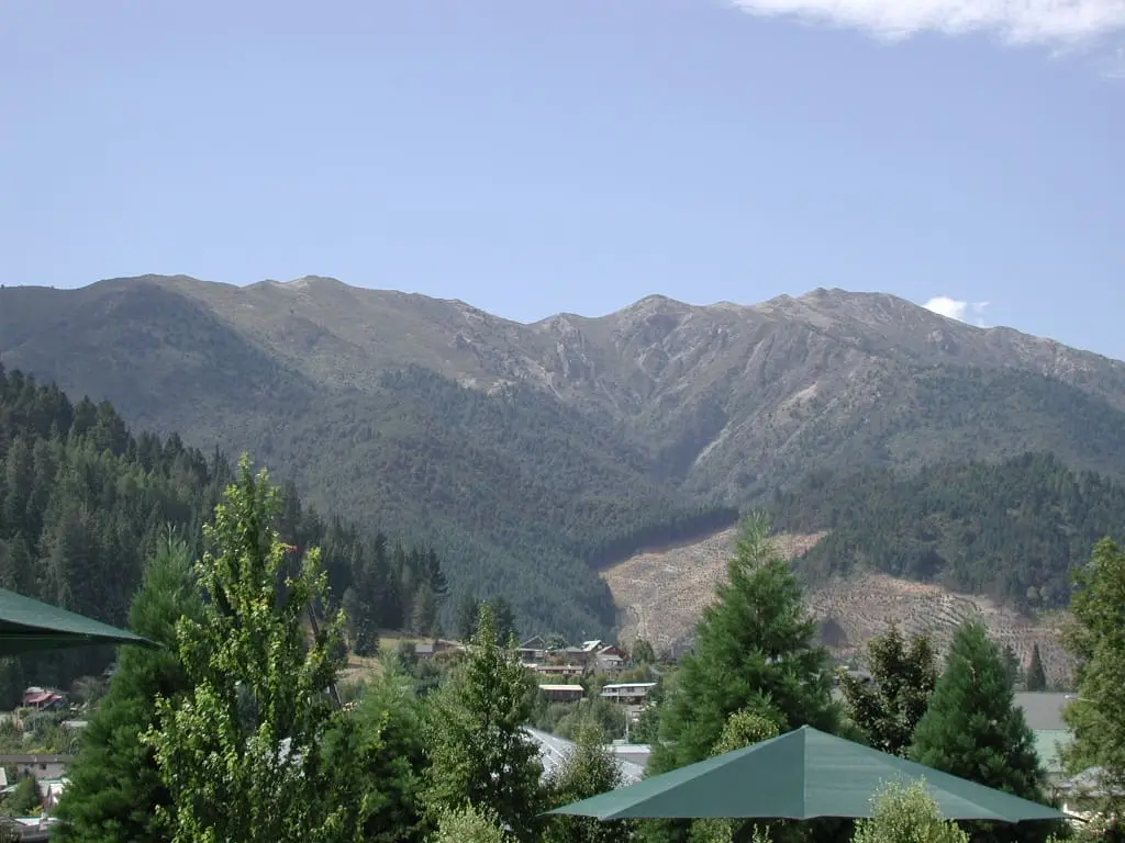 Mount Isobel rising above pine trees and green shade sails in Hanmer Springs village