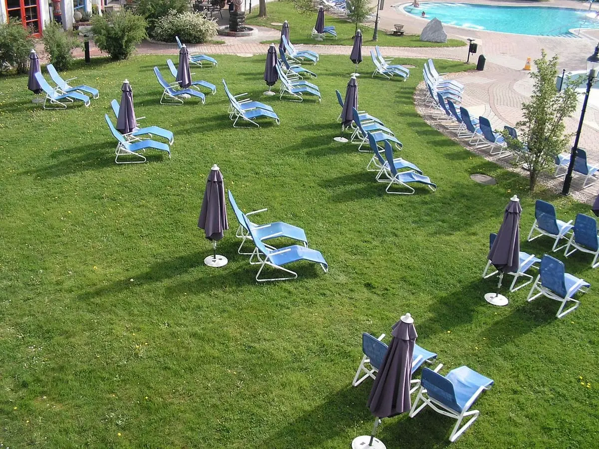 Sun loungers and parasols on the lawn beside the outdoor thermal pool at Rogner Bad Blumau