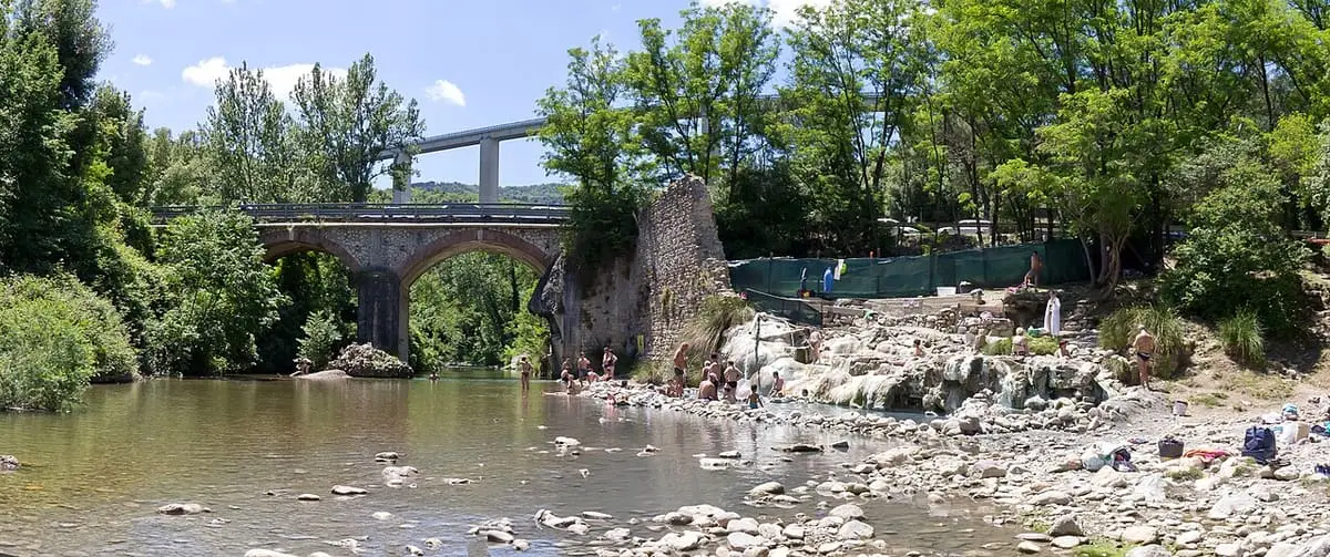 Rock rimmed thermal pools along the Farma river at Petriolo with the old stone bridge behind
