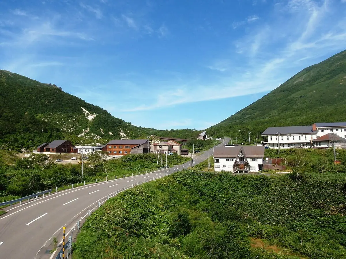 Road leading to the inns of Niseko Goshiki Onsen between green mountain slopes