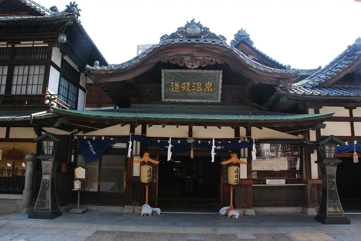 Ornate public entrance of Dogo Onsen Honkan with a carved gable and name plaque