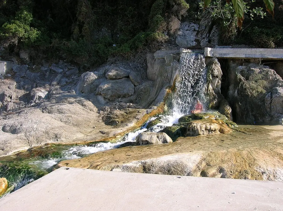 Thermal water falling over rocks into a pool beside a concrete ledge at Thermopylae