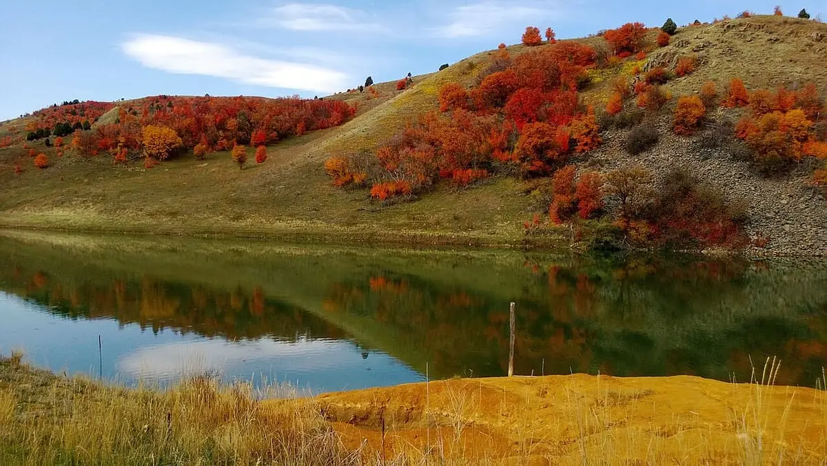 Autumn colored hillside above a calm reservoir shoreline near Maple Grove Hot Springs