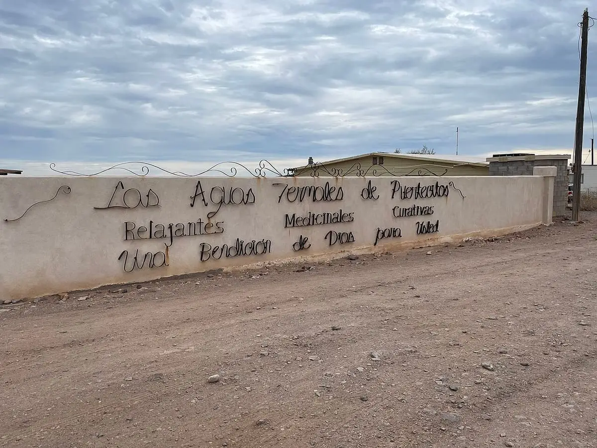 Whitewashed wall with a wrought iron sign for the thermal waters of Puertecitos