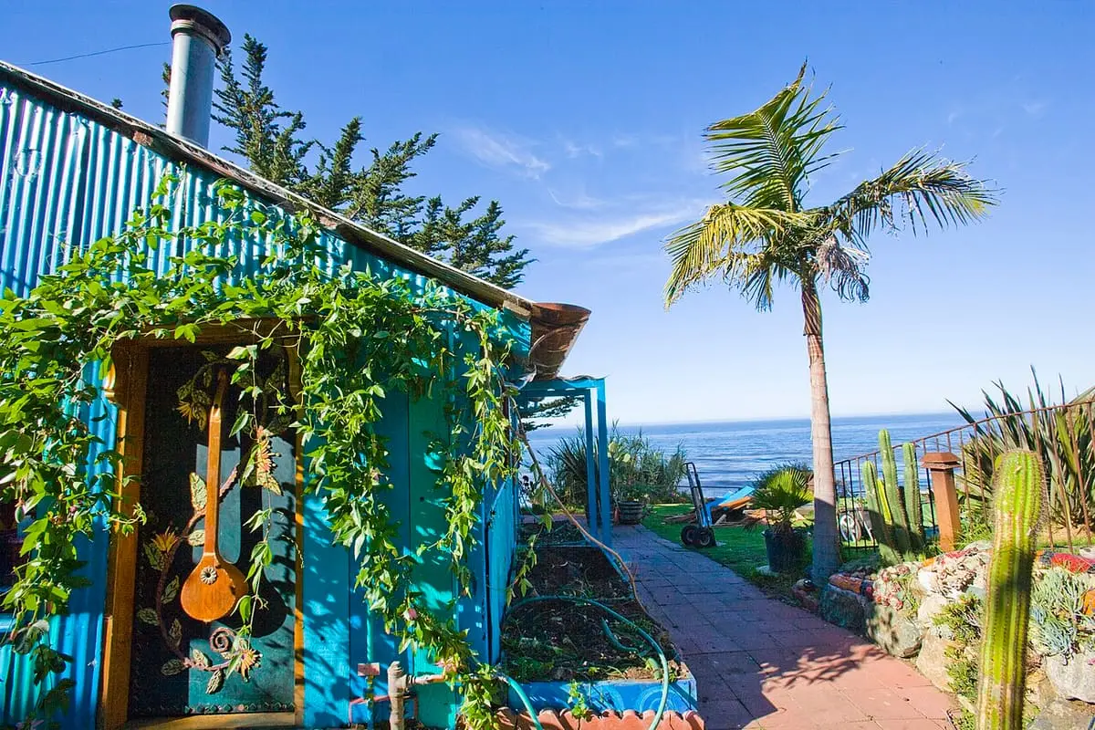 Blue Art Barn with vines and palm trees above the Pacific at Esalen Institute