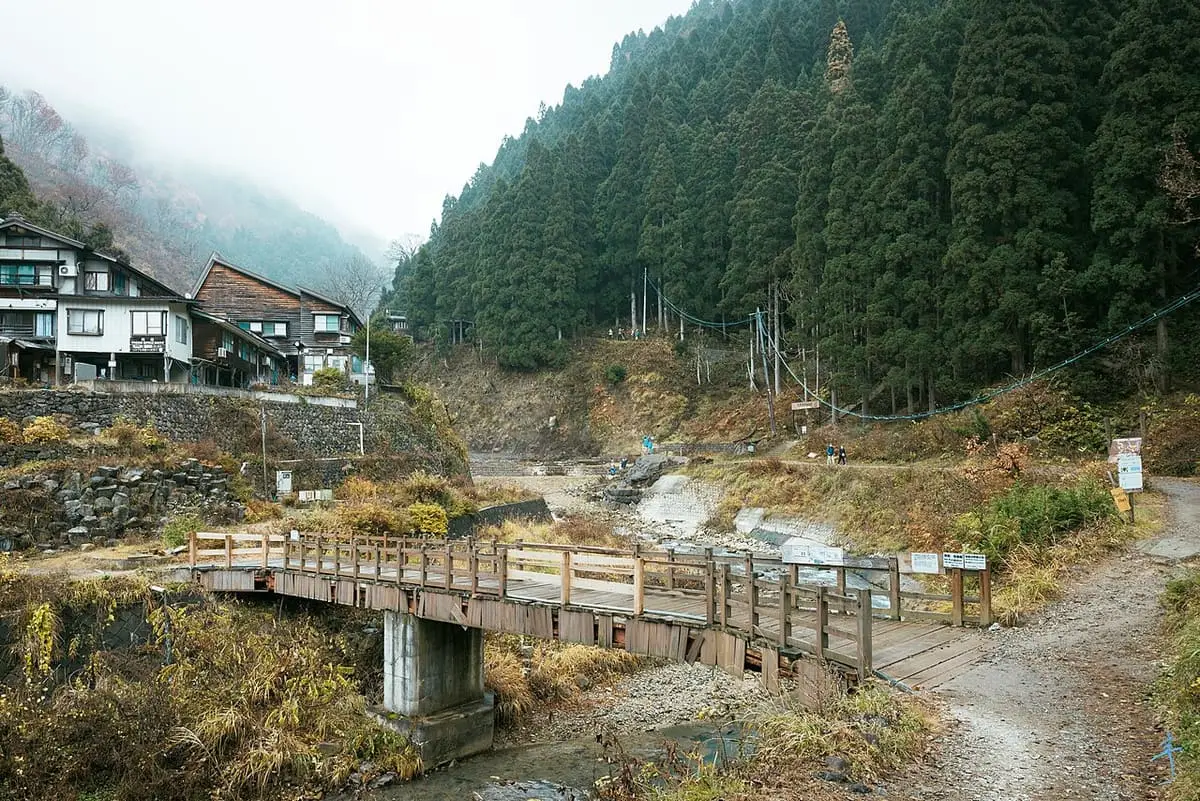 Wooden footbridge and riverside inn in the forested Jigokudani valley near the monkey park