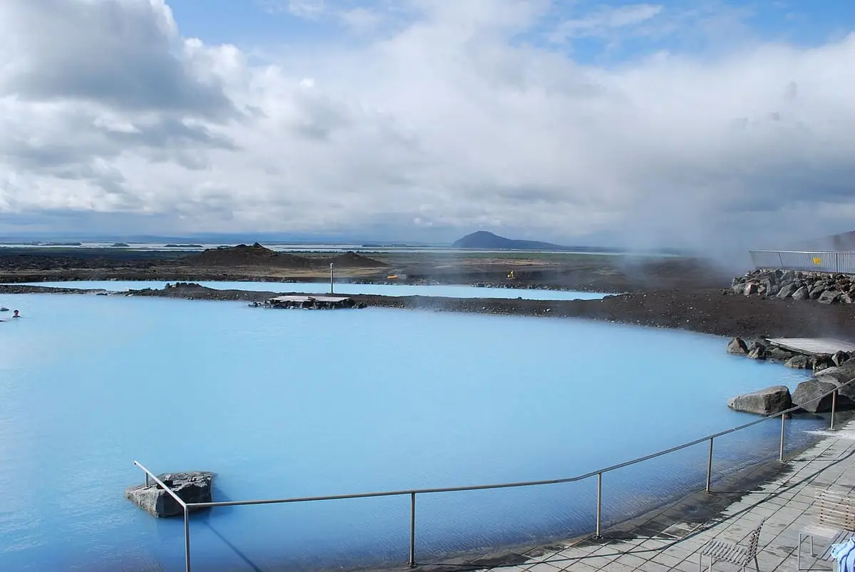 Steam drifting over the pale blue lagoon at Mývatn with a railing along the edge
