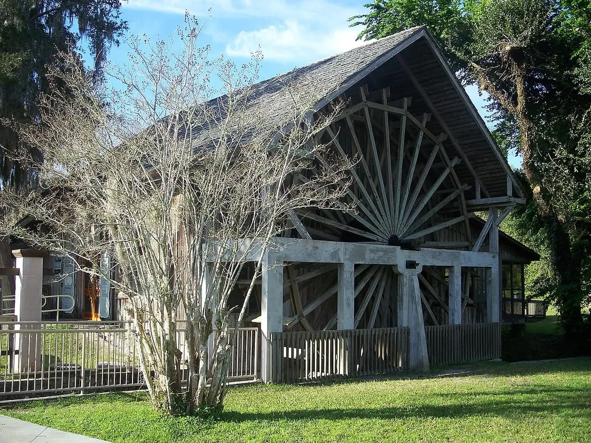 Old Spanish sugar mill building with a large wooden waterwheel at De Leon Springs State Park