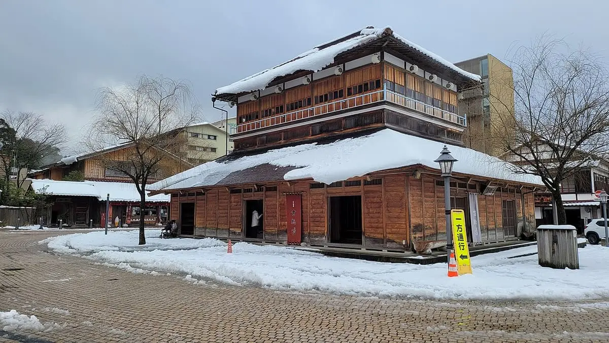Kosoyu bathhouse of Yamashiro Onsen with snow on its roofs and square