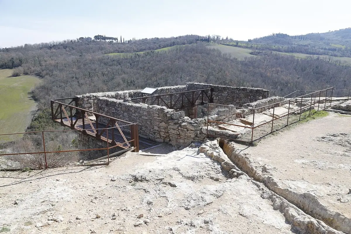 Stone ruins of the old mills with railings above a travertine water channel at Bagno Vignoni