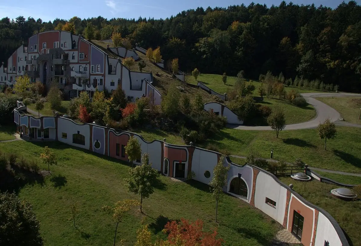 Hillside rows of green roofed Hundertwasser buildings across the Rogner Bad Blumau resort grounds