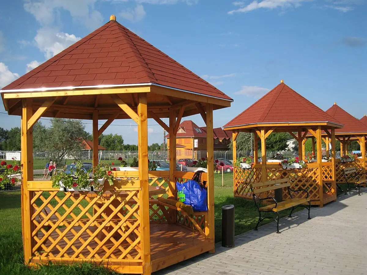 Wooden gazebos with red roofs along a path in the Tiszaújváros bath grounds