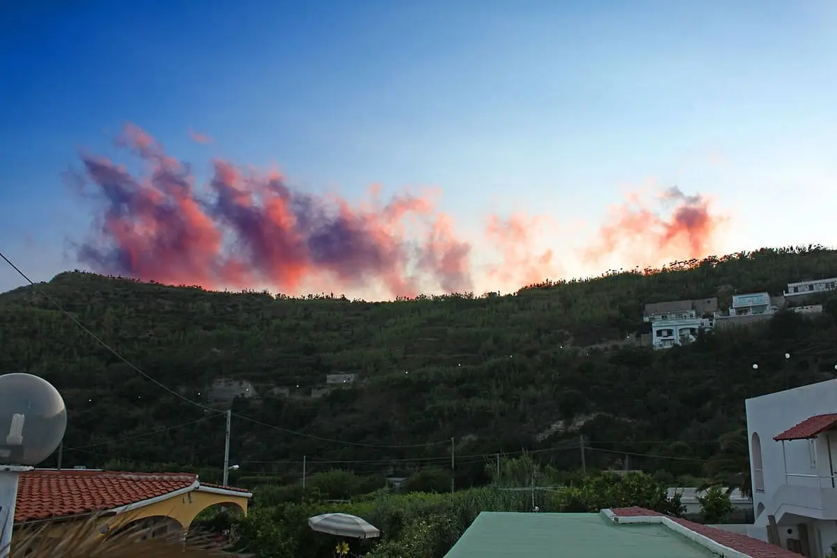 Pink sunset clouds above the green hillside over Baia di Sorgeto