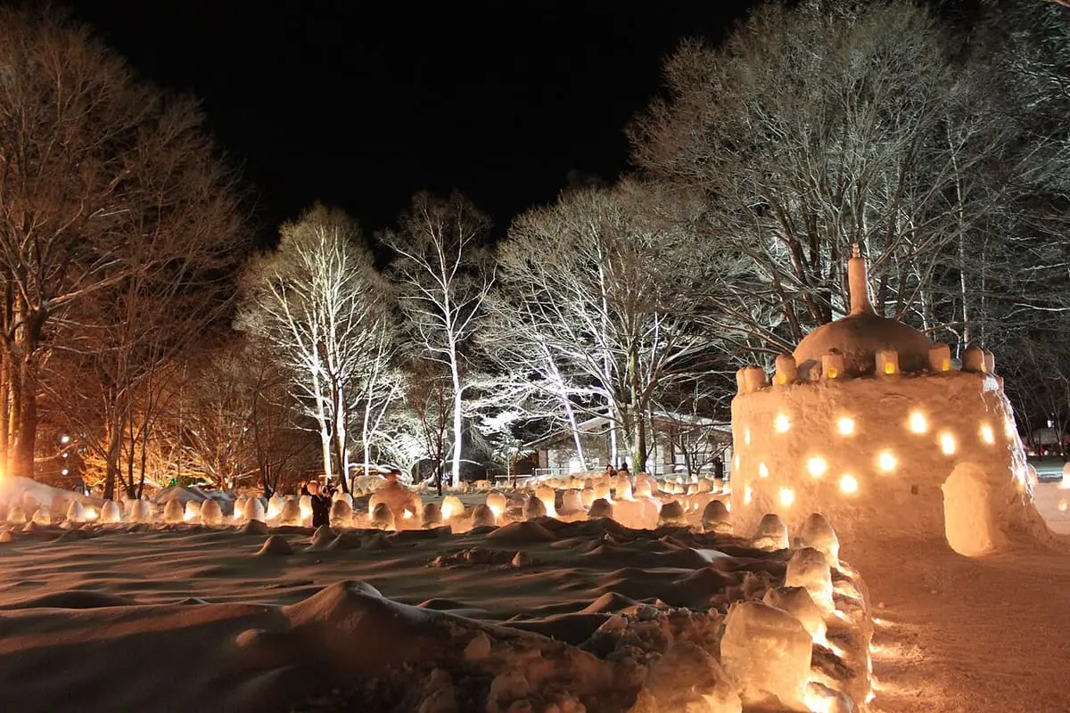 Snow lanterns and a lit snow stupa glowing at night in Okunikko Yumoto Onsen