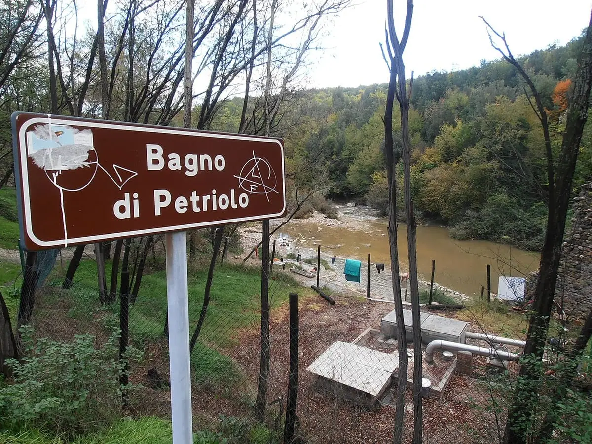 Brown Bagno di Petriolo road sign above the Farma river valley and the riverside pools