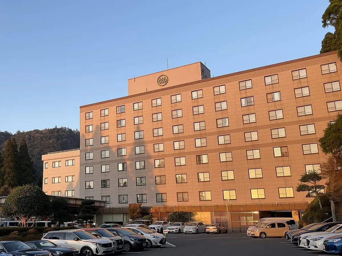 Kirishima Hotel building in the Kirishima Onsen area beside a parking lot at golden hour