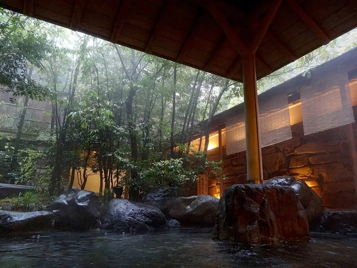 Rock lined open air bath under a wooden roof at Nishimuraya Hotel Shogetsutei in Kinosaki Onsen