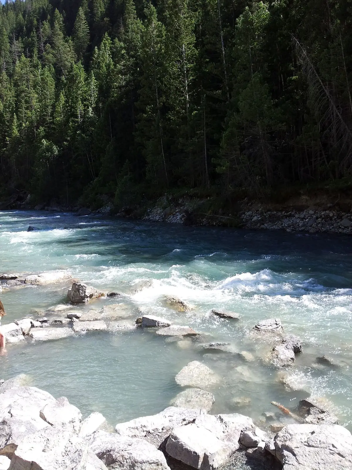 Shallow rock pools at Lussier Hot Springs at the edge of the fast Lussier River