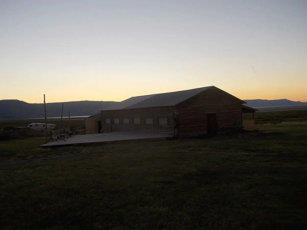 Wooden building at Summer Lake Hot Springs silhouetted against an orange sunset sky