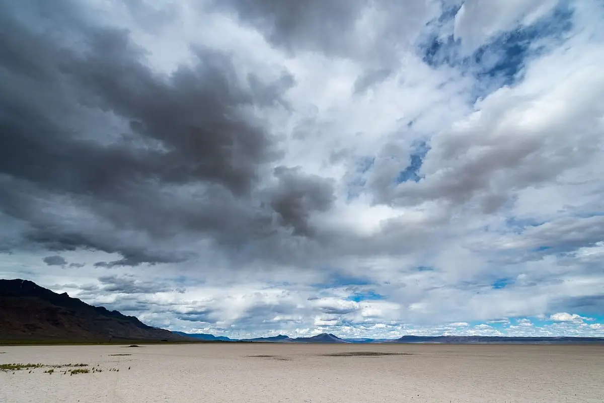 Wide Alvord Desert playa below dramatic storm clouds and a low ridge on the horizon