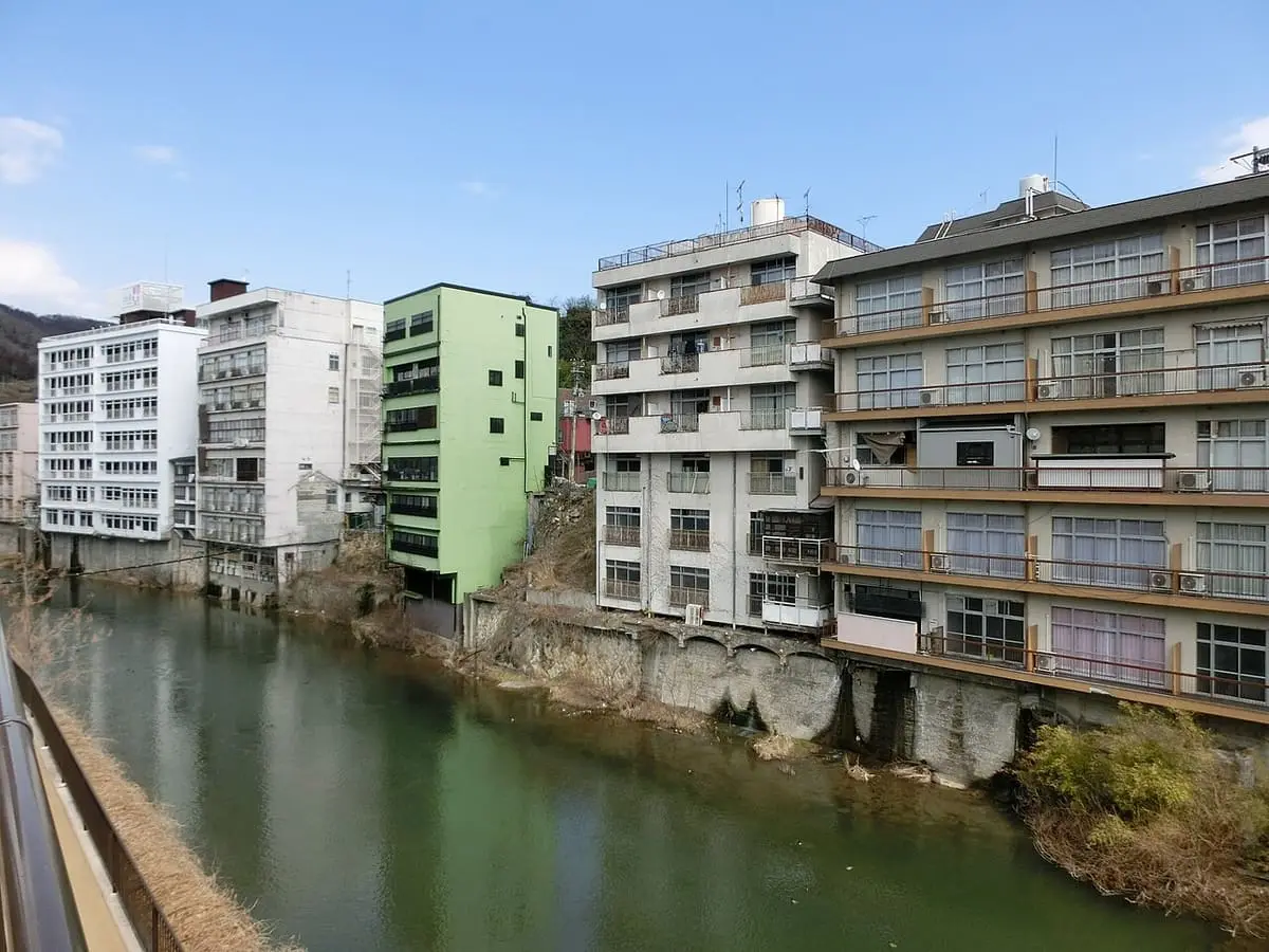 Row of ryokan and hotel buildings on the rocky bank of the river at Iizaka Onsen