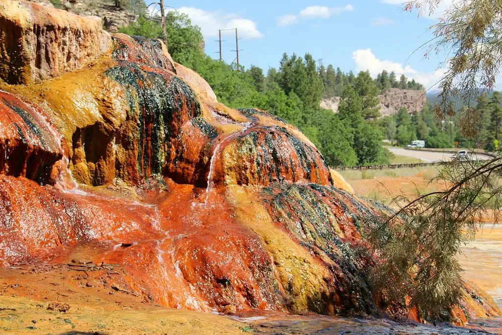 Close view of orange, yellow and dark mineral deposits on the Pinkerton Hot Springs rock pile