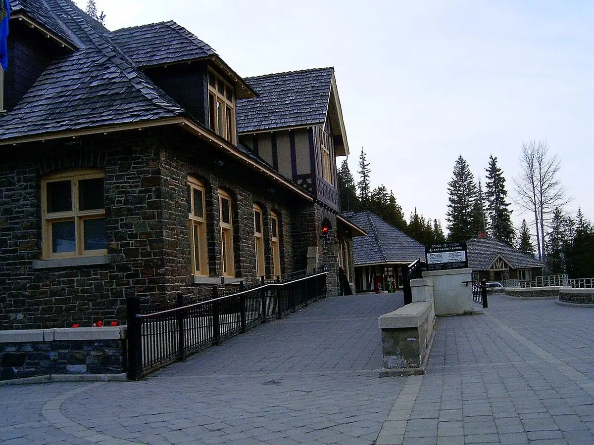 Stone entrance building and paved plaza on the upper level of Banff Upper Hot Springs