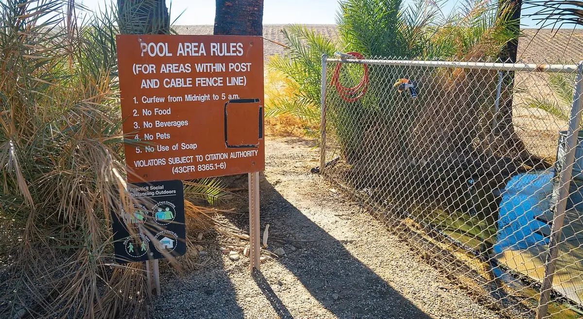 Pool area rules sign beside the fenced soaking area at the Hot Springs Long Term Visitor Area